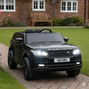 Front profile of a black SUV ride-on car with functional LED headlights illuminated on a brick-paved driveway.