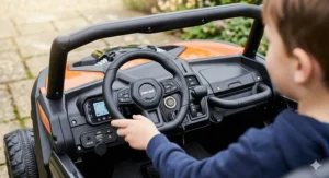 Close-up detail of the Can-Am Maverick ride-on dashboard showing the textured steering wheel, start button, and media player controls.