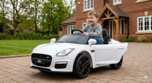 Small boy sitting on a blue electric ride-on tractor with a front loader and a trailer filled with toys.