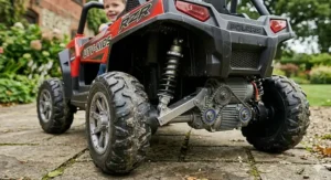 Detailed shot of the rear coil spring suspension system and rugged off-road tyres on a Polaris RZR style kids electric car.