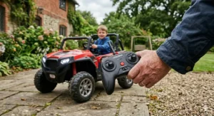 A parent's hand holding a 2.4G wireless remote control used to supervise and steer the Polaris RZR style kids electric car.