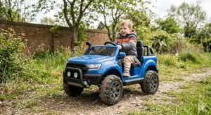 A mother using a parental remote control to guide her young son in a black electric ride-on car on a pavement.
