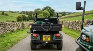 Rear view of a road-legal two seat electric buggy featuring a UK number plate, indicators, and side mirrors on a tarmac road.