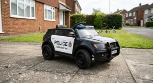 Red foot-to-floor ride-on car for toddlers with a steering wheel and horn on a sunny stone patio.