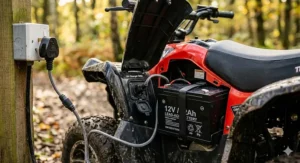 The 12v rechargeable battery of an electric quad bike being charged via a standard UK 3-pin mains plug and cable.