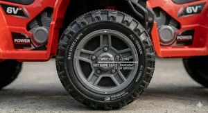 Technical close-up of the deep tyre tread on a red 6v quad bike for toddlers, highlighting its suitability for use on garden grass and flat ground.