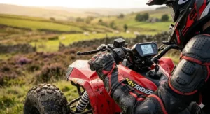A black and grey 24v quad bike for older kids parked on a rocky outcrop overlooking a scenic valley.