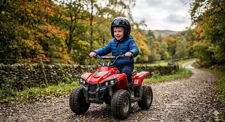 A child wearing a safety helmet riding a red 12v quad bike on a gravel path in the British countryside. 12v quad bike