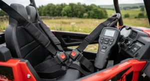 Close-up of the interior of a kids' 4x4 UTV showing the secure safety harness and the parental remote control handset.