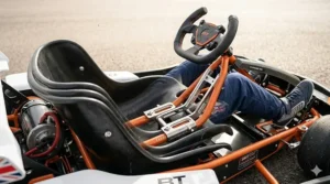 A photorealistic detailed cockpit view showing the black contoured bucket seat of the drift kart with annotations detailing the intricate metal and orange adjustable track system, demonstrating its multiple positions to accommodate the growing legs of child and teenager drivers.