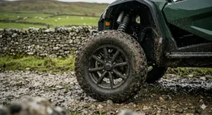Deep-tread off-road tyres on an electric buggy with high-clearance suspension, caked in mud from a UK trail.