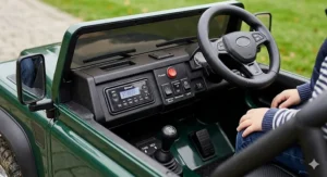Detail shot of the interior dashboard of a kids' motorised buggy, showing the steering wheel, power switch, gear stick, and media console.