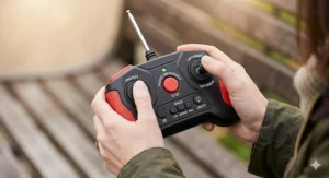 A detailed close-up of a white 2.4Ghz parental remote control unit, showing the aerial and a parent's hands operating the buttons, with a blurred park background.