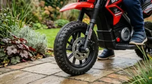 Close-up photorealistic illustration showing removable stabiliser wheels on a red 12v sport electric motorbike for kids.