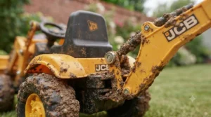 Rear view of a rechargeable battery-powered ride-on tractor equipped with a rear-mounted digger.