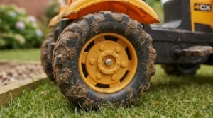 Detail shot of the durable, deep-tread tyres on a kids' ride-on tractor with a digger attachment.