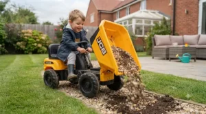 A working tipping bed on a yellow JCB ride-on dumper being loaded with garden soil during outdoor play.