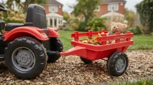The detachable red trailer for the 12V tractor, filled with autumn leaves and a teddy bear.