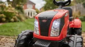 Front view of the red 12V kids' ride-on tractor with its LED headlights illuminated.