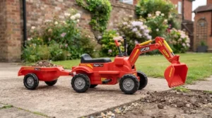 Red pedal-powered ride-on digger toy featuring a detachable trailer, parked on a driveway.