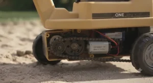 Rechargeable battery-powered ride-on excavator toy parked on a driveway