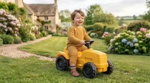 Toddler sitting on a yellow foot-to-floor farm tractor toy.
