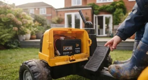 Young toddler sitting safely on a pedal-powered JCB ride-on digger outdoors