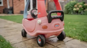 Rear view of the pink Cozy Coupe featuring the integrated parent push handle on the roof.
