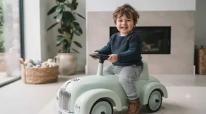 A close-up shot of a toddler's hands gripping the horn-equipped steering wheel of an outdoor foot-to-floor car.