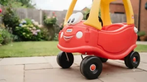 Front view of the classic red Little Tikes Cozy Coupe showing its friendly smiley face grille and black steering wheel.