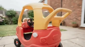 Rear view of the classic red Little Tikes Cozy Coupe highlighting the integrated parent push handle on the roof.
