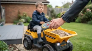 Parent using a remote control to guide a toddler safely in their electric ride-on dumper truck on a driveway.