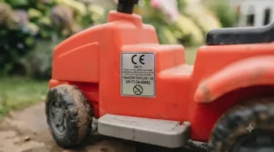 A clear view of the CE mark and safety information sticker on the chassis of a ride-on tipping truck, confirming compliance with UK toy safety standards.