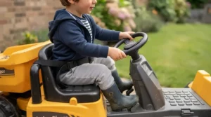 Toddler safely seated and steering a battery powered ride on dumper truck