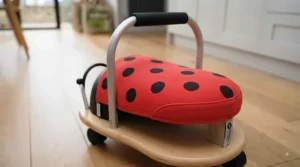 Young toddler happily riding the small Wheelybug ladybird toy indoors, demonstrating child-friendly sizing.