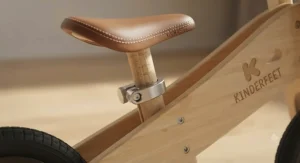 Close-up of an adjustable seat clamp on a wooden balance bike designed to grow with a toddler from age two.