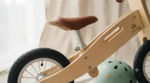 Close-up of the adjustable padded seat on a wooden balance bike designed for growing toddlers.