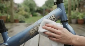 A parent wiping down a low-maintenance metal balance bike after a muddy ride in the woods.