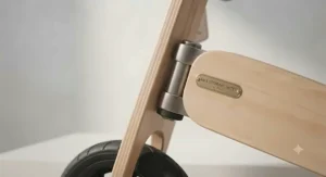 Detail view of the restricted steering limiter on a wooden balance bike to prevent sharp turns and sudden falls.