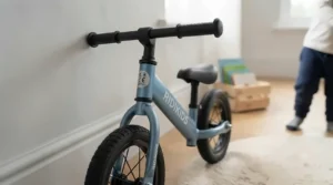 Toddler playing with their first balance bike indoors on a wooden playroom floor
